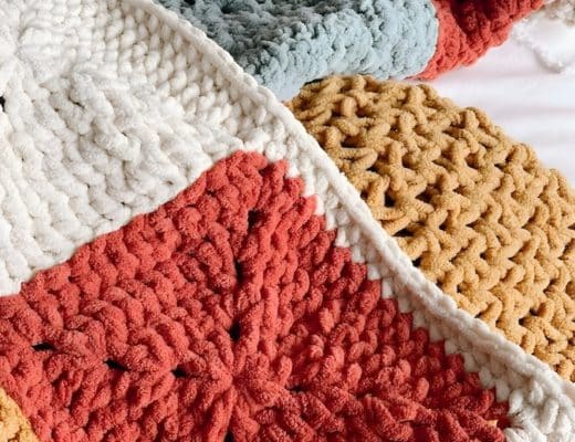 a person holding a crocheted blanket on top of a bed